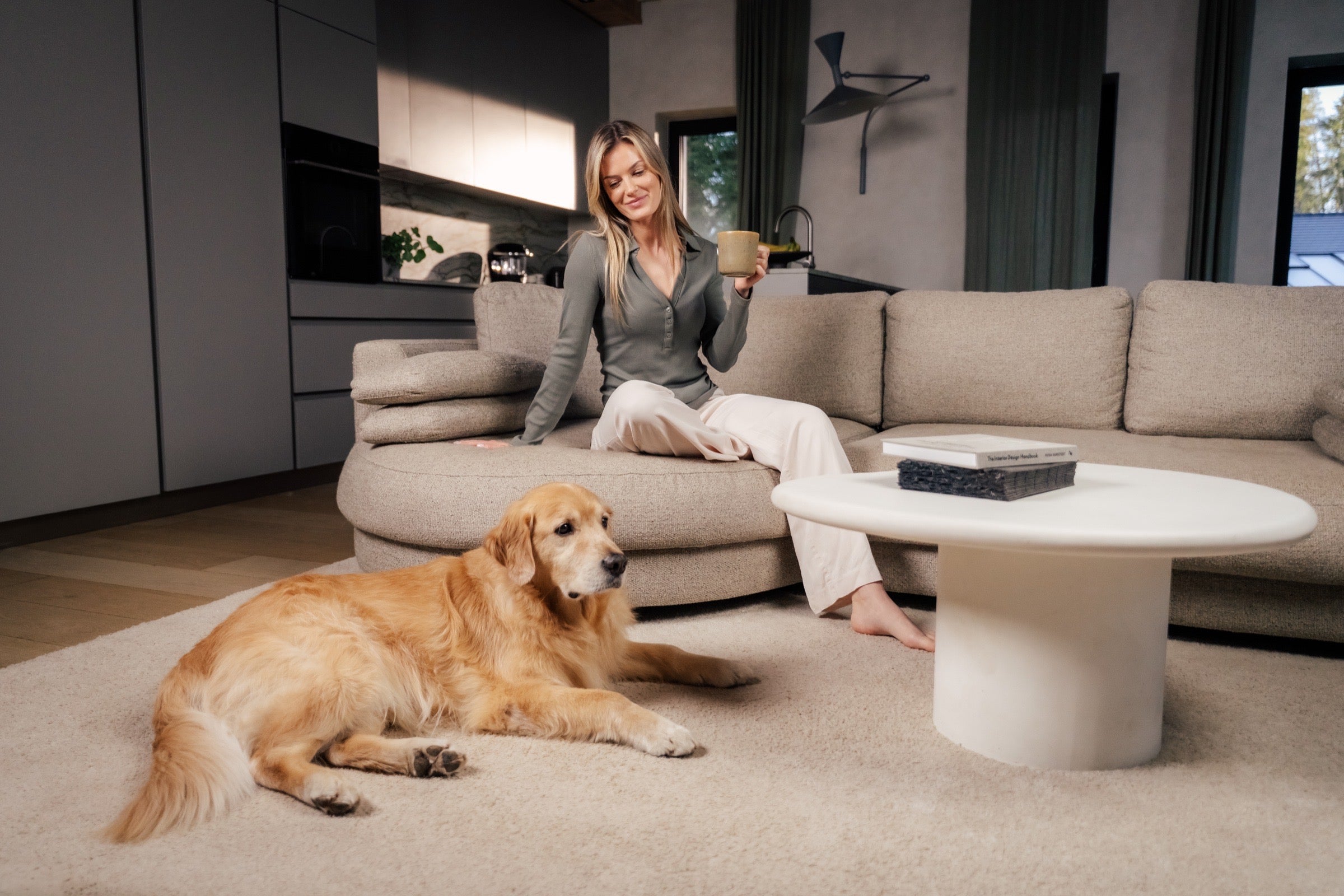 Woman sitting on a couch with a dog in a modern living room